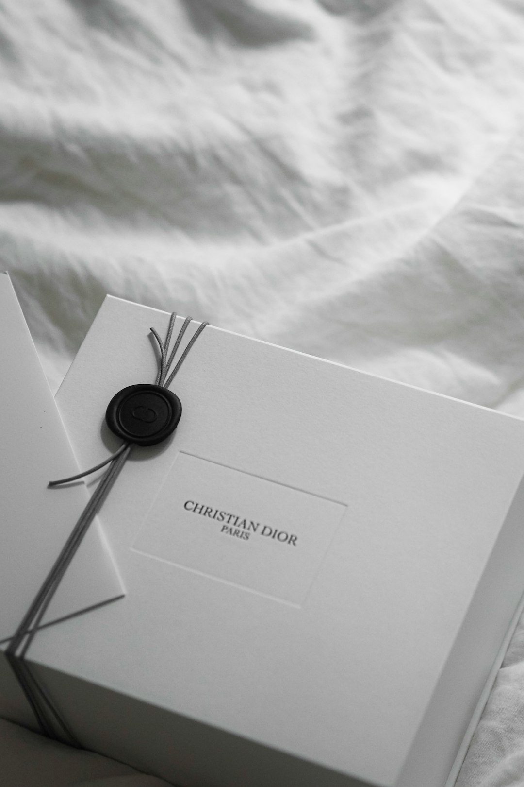 christian-dior-gift-box-with-wax-seal-on-white-fabric-cnflh-f-8oa